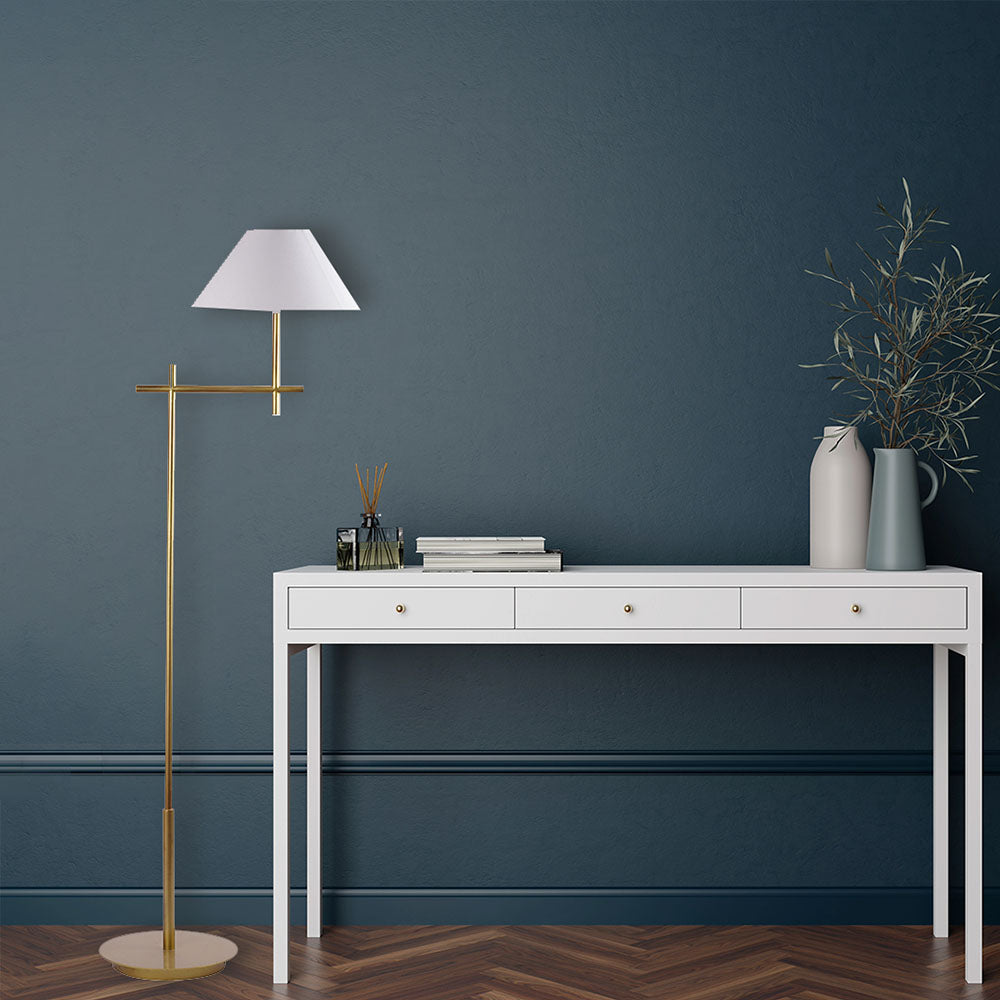 Tall, minimalistic design golden floor lamp with shade placed next to a console table.