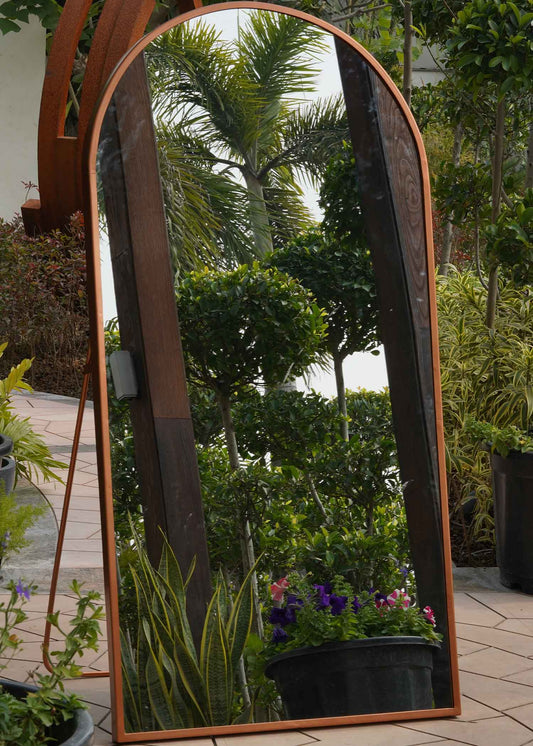 Close-up view of a curved metallic full length floor mirror.