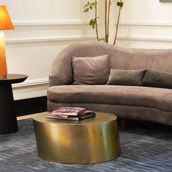 Elliptical shape golden metallic coffee table in a living room set-up.