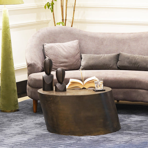 Elliptical shape cola black colored metallic coffee table in a living room set-up.