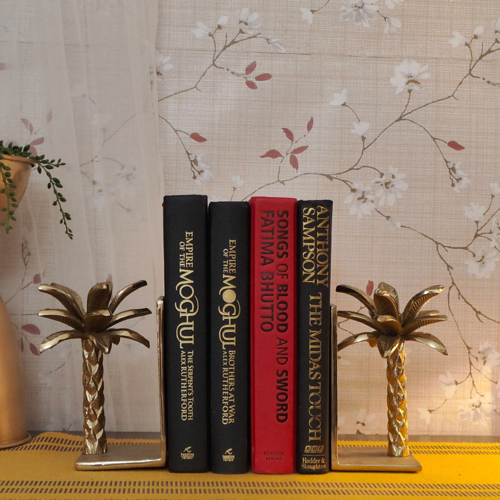 Golden metallic palm tree shaped bookends with 4 books placed in between.