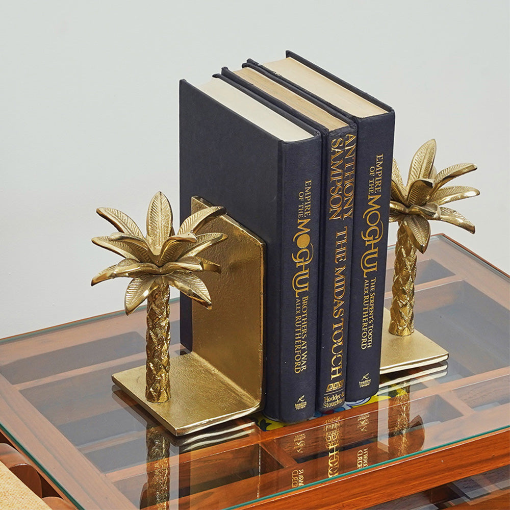 Golden metallic palm tree shaped bookend. with 3 books in between at a side angle