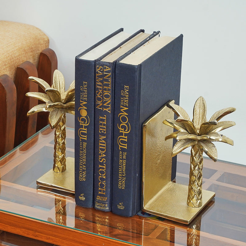 Golden metallic palm tree shaped bookend placed on a table, side angle.