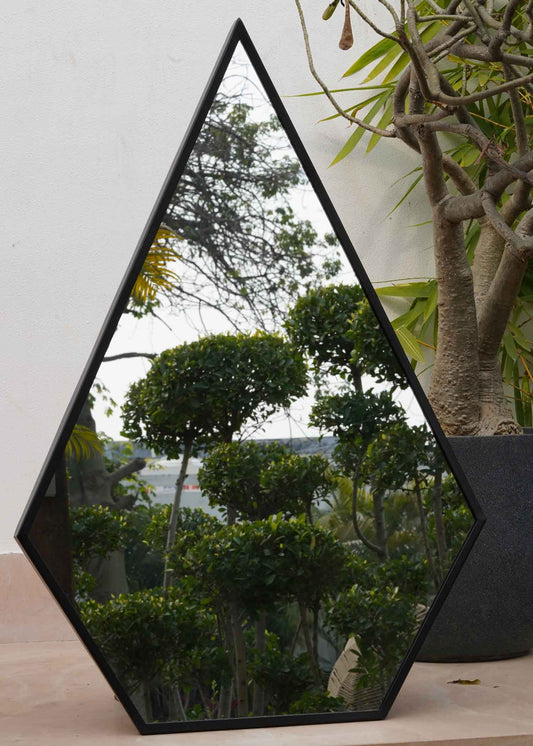 Close-up view of a tall metallic black pentagon framed mirror.