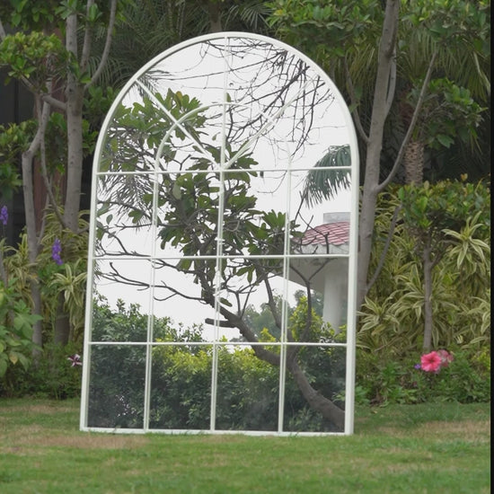 Artistic short video of a lady walking by a large white window shaped mirror, feeling the curved edges of the mirror.