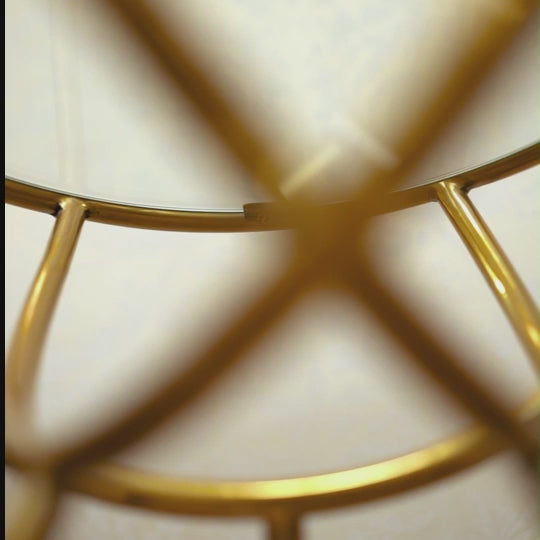 Multi-angle close-up video of a golden metallic side table with a glass top.