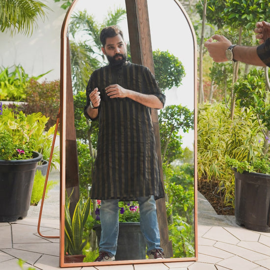 GIF video of a male model styling in front of a curved metallic full length floor mirror.