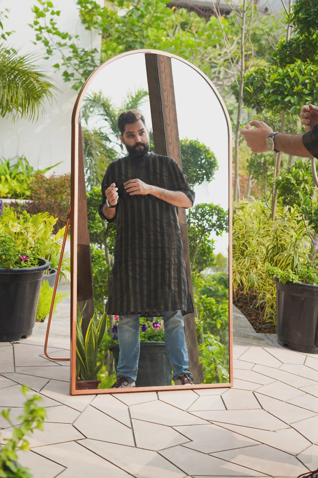 GIF video of a male model styling in front of a curved metallic full length floor mirror.