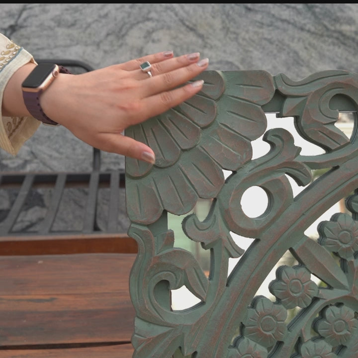 A hand-model touching the beautiful engravings of a mango wood wall art.