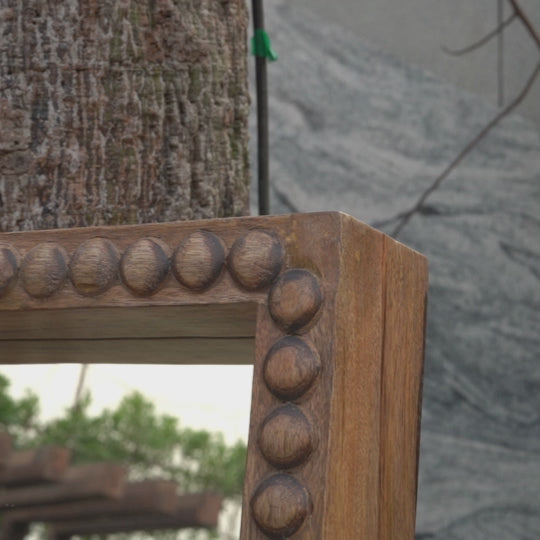 Closeup video showing detailed wood work on a large floor mirror.