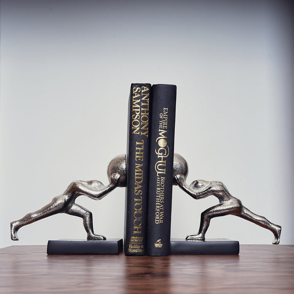 Metallic silver colored bookends set of 2 human figures pushing from opposite direction with 2 books placed in between.