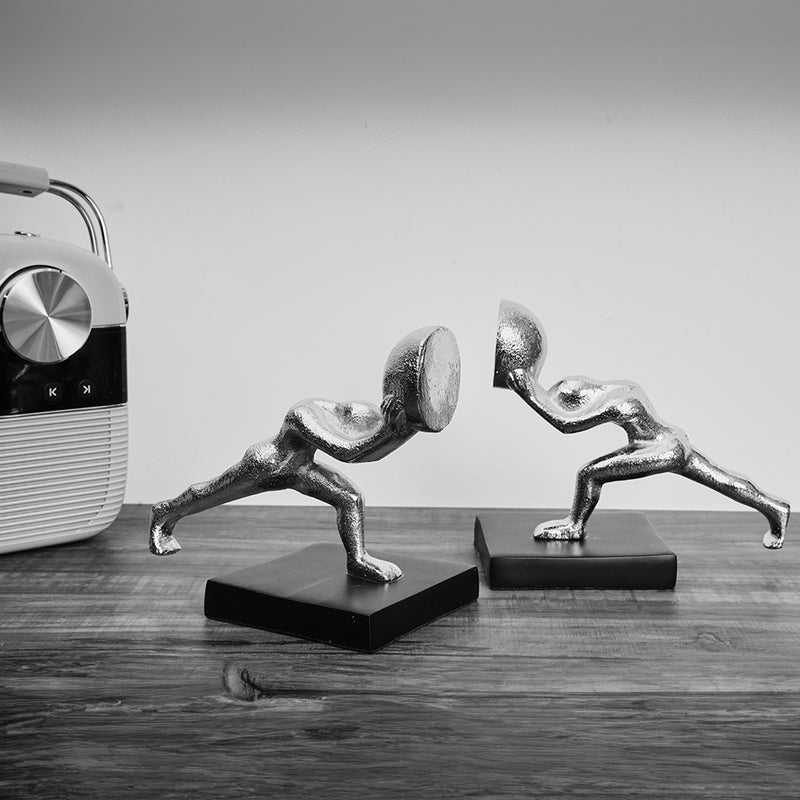 Metallic silver colored bookends set of 2 human figures pushing from opposite direction in a black & white contrast.