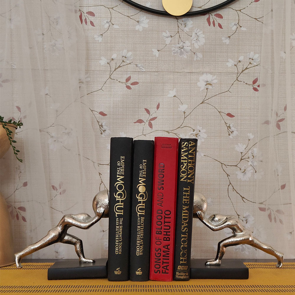Metallic silver colored bookends set of 2 human figures pushing from opposite direction with 4 books placed in between.