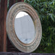 Large circular mirror in hand-carved mango wood frame- side view.