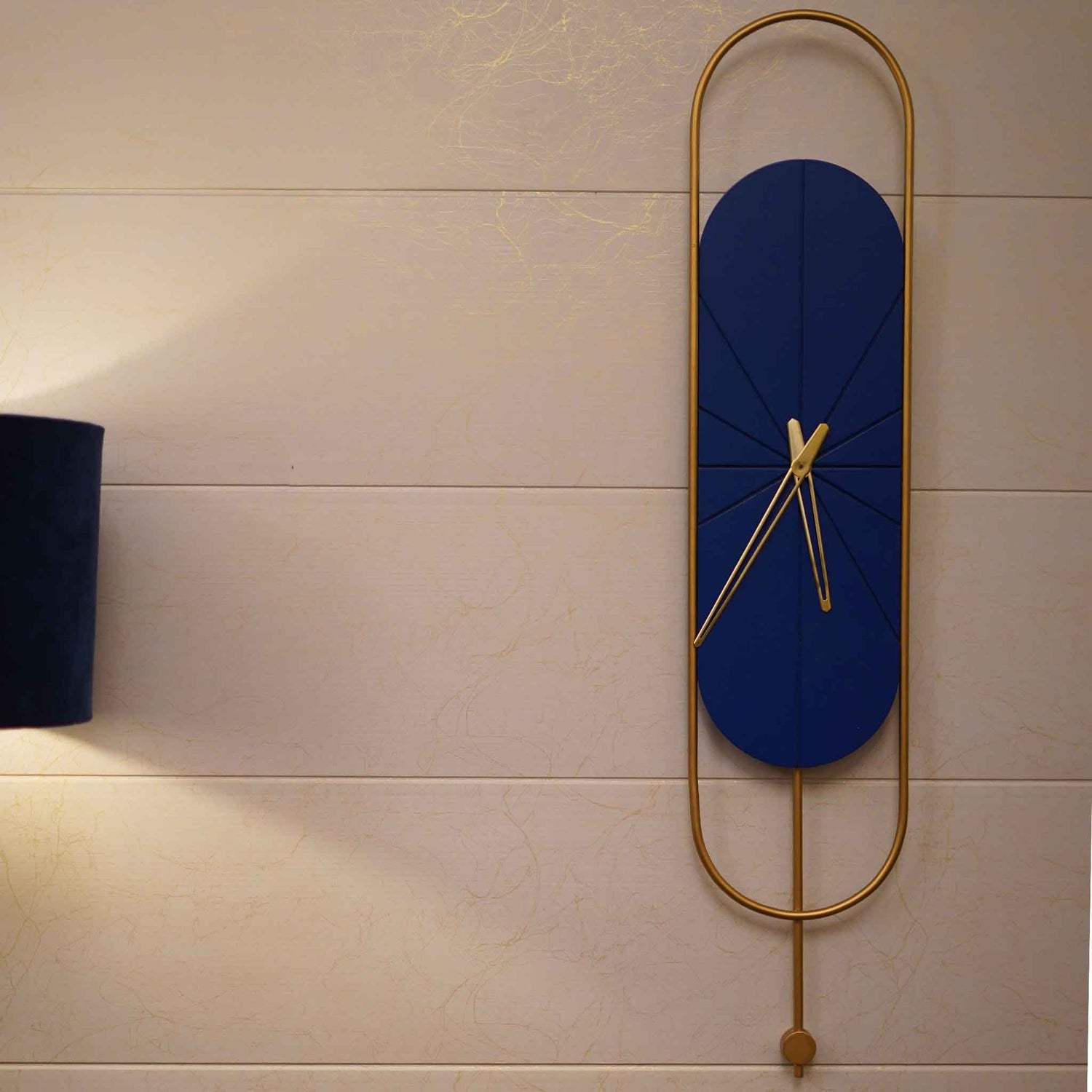 Long blue and golden colored metallic wall clock with pendulum design.