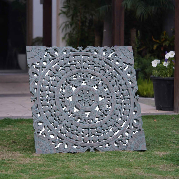 A large square wooden hand-carved wall hanging with a mirror base.