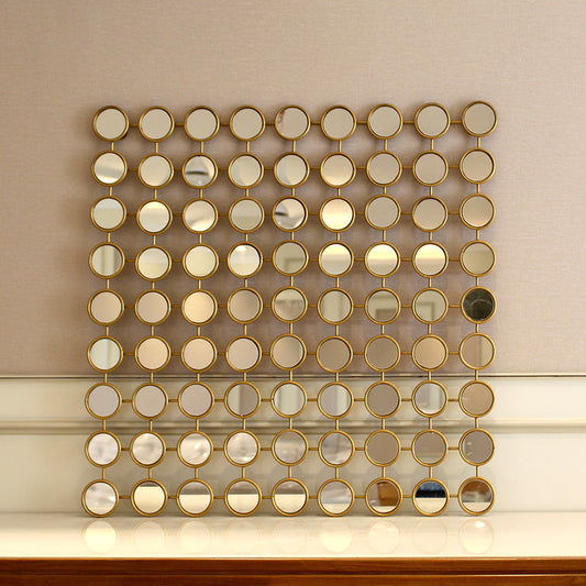 Front view of a modern metallic wall art made of 81 small mirrors placed on a console table.