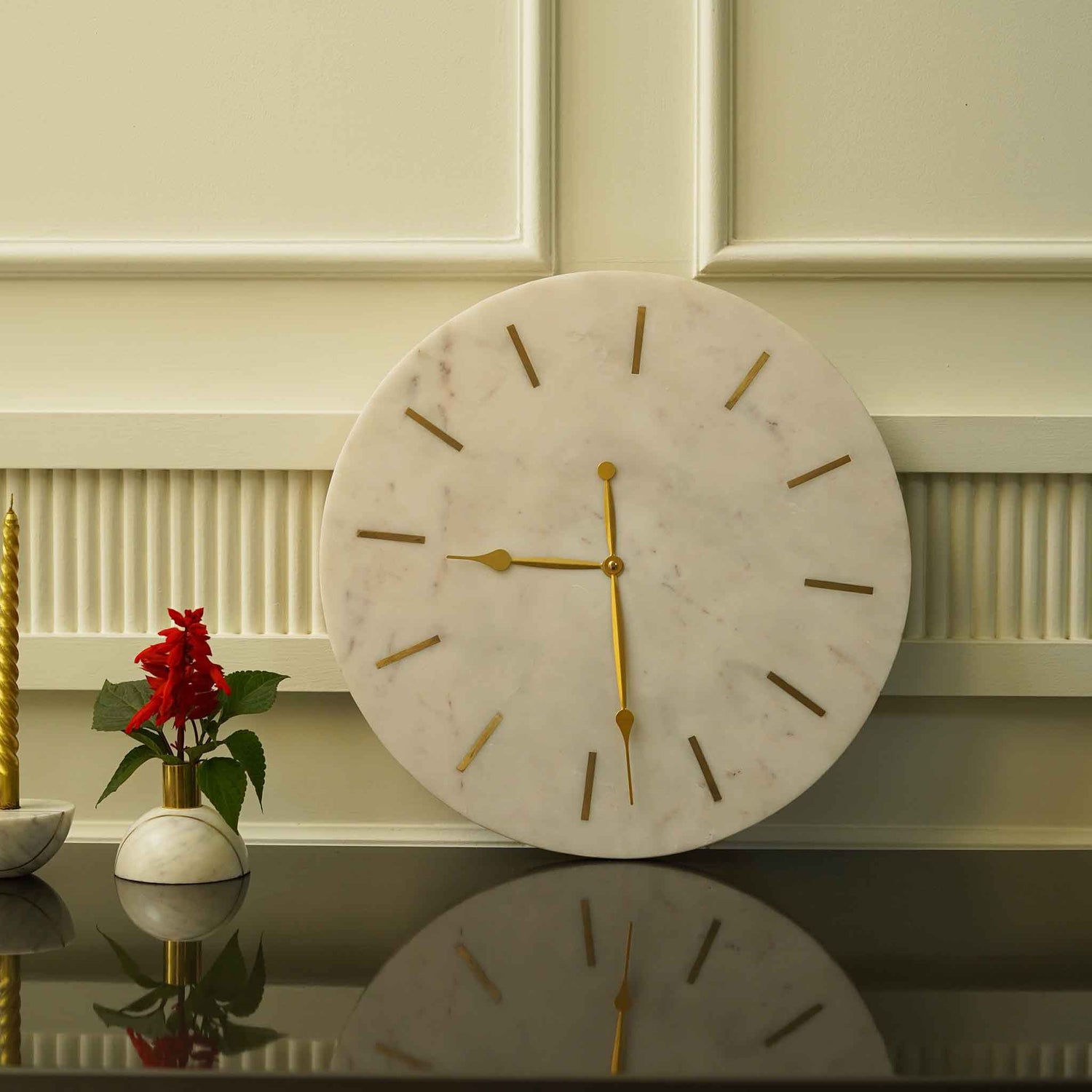 A large and heavy white marble clock with golden hands and hours marked with brass inlay.