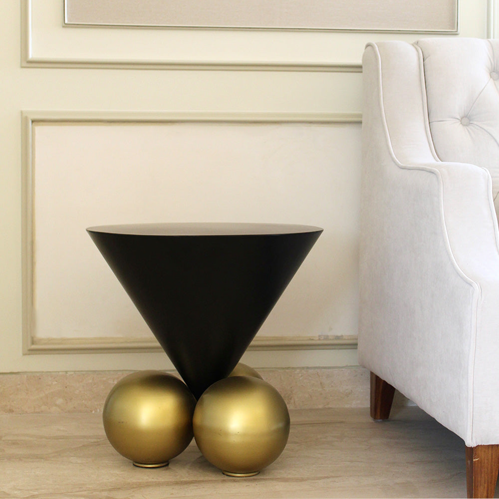 Modern design black triangle cone coffee table with 3 spherical balls on base in a living room setup.