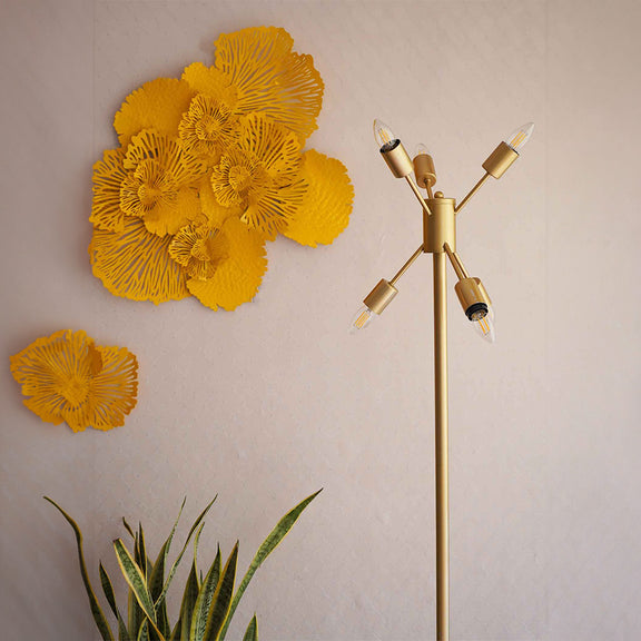 A golden colored modern floor lamp with 6 bulbs is placed in a living room set-up.