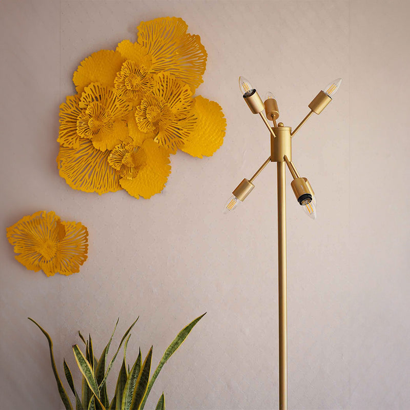 A golden colored modern floor lamp with 6 bulbs is placed in a living room set-up.