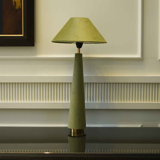 Front view of a green velvet lamp placed on a console table.