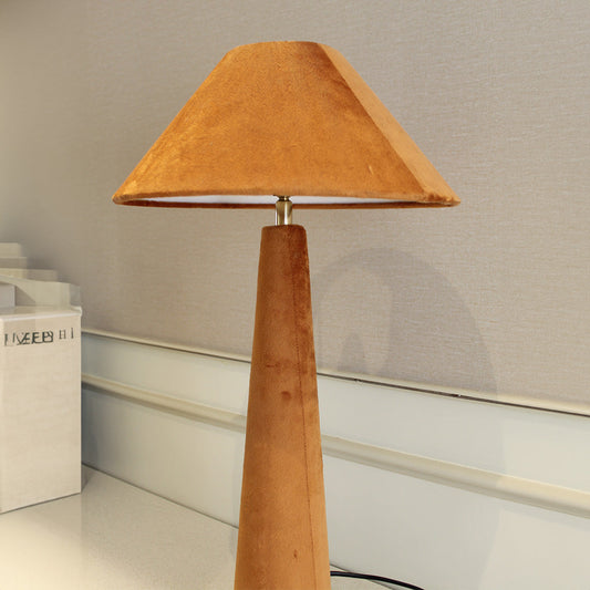 Front view of a orange velvet lamp placed on a living room console table.