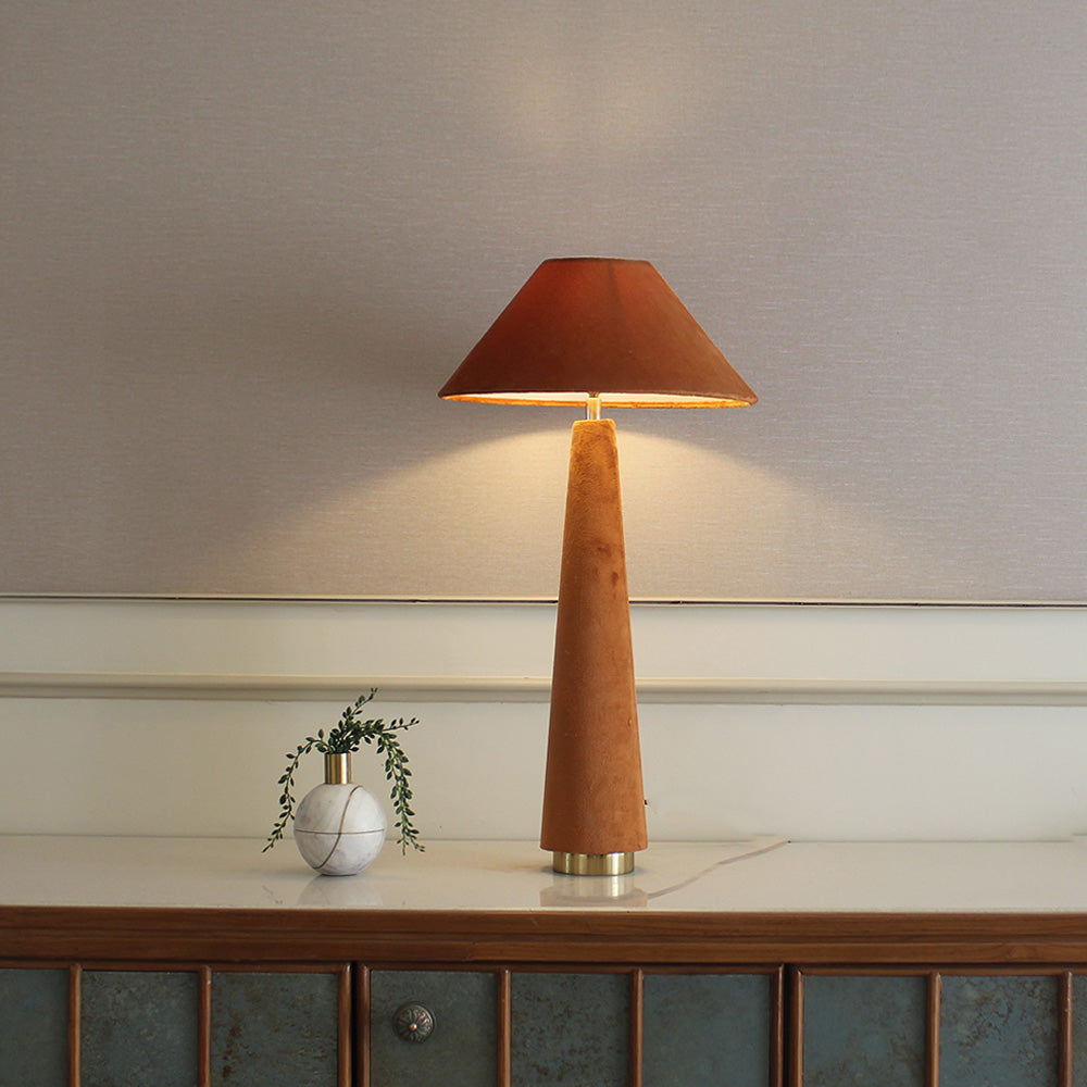 Front view of a orange velvet lamp placed on a console table.