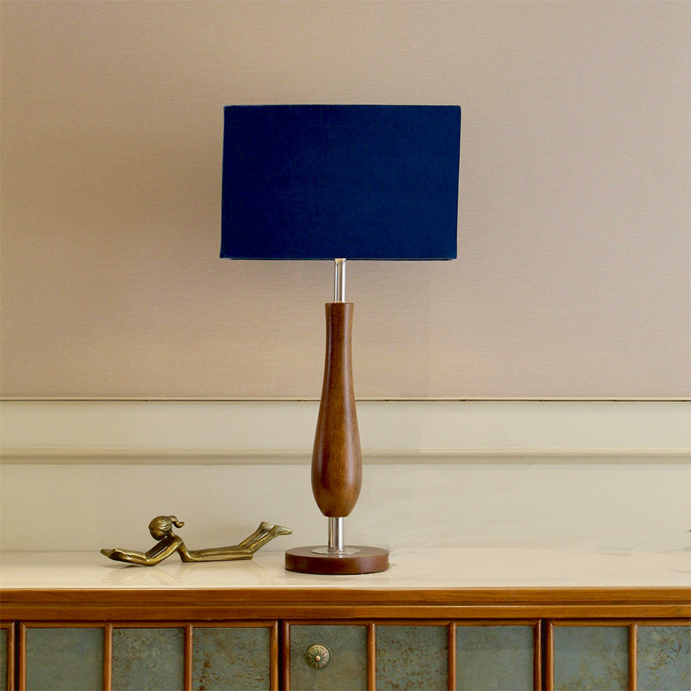 Wooden table lamp with blue shade on a console table.